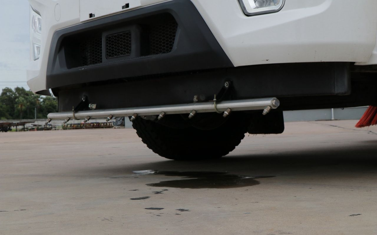 Front spray bar on a sweeper body